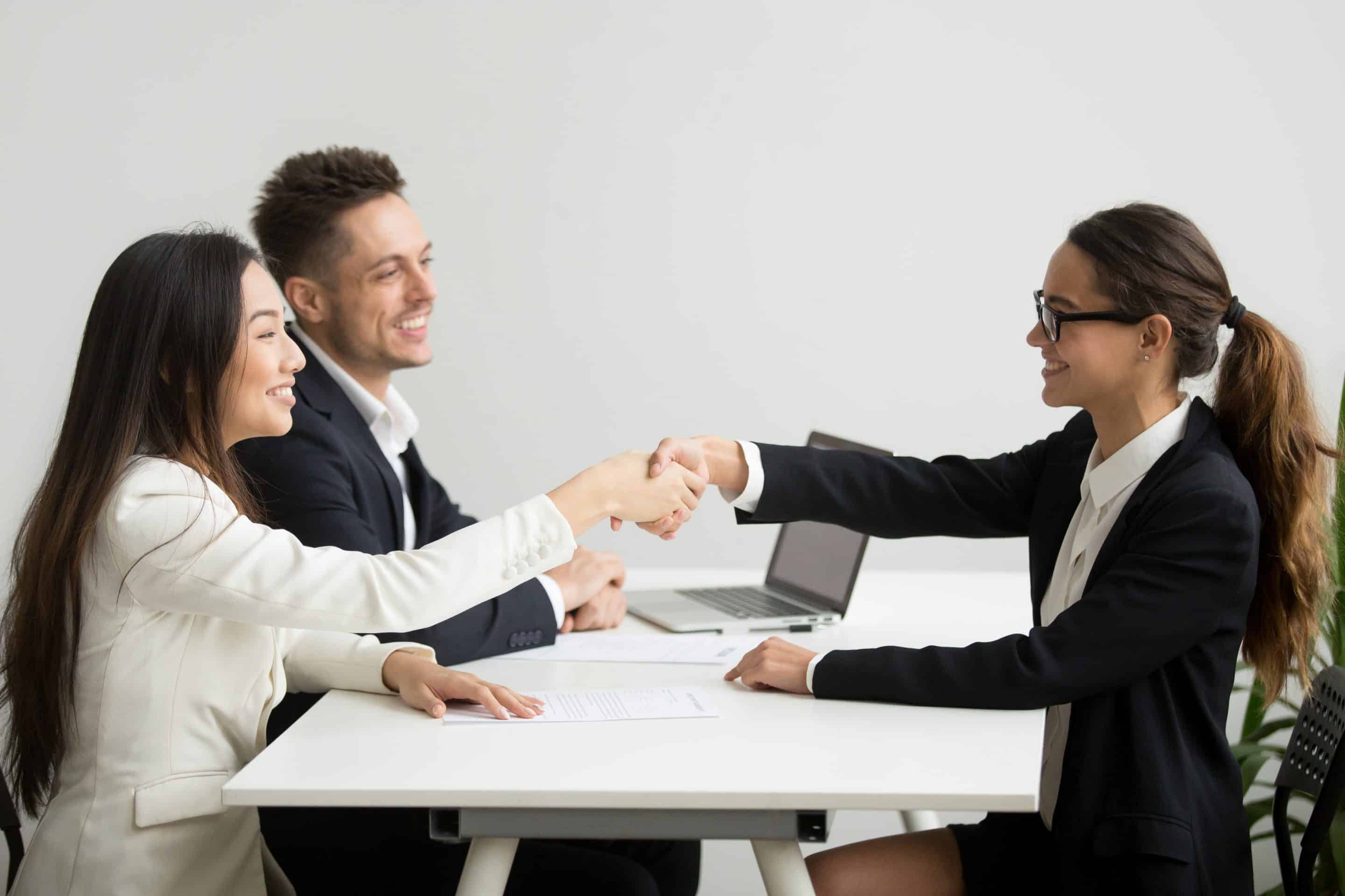 Smiling diverse businesswomen shake hands at group meeting, deal Healthcare Recruiter